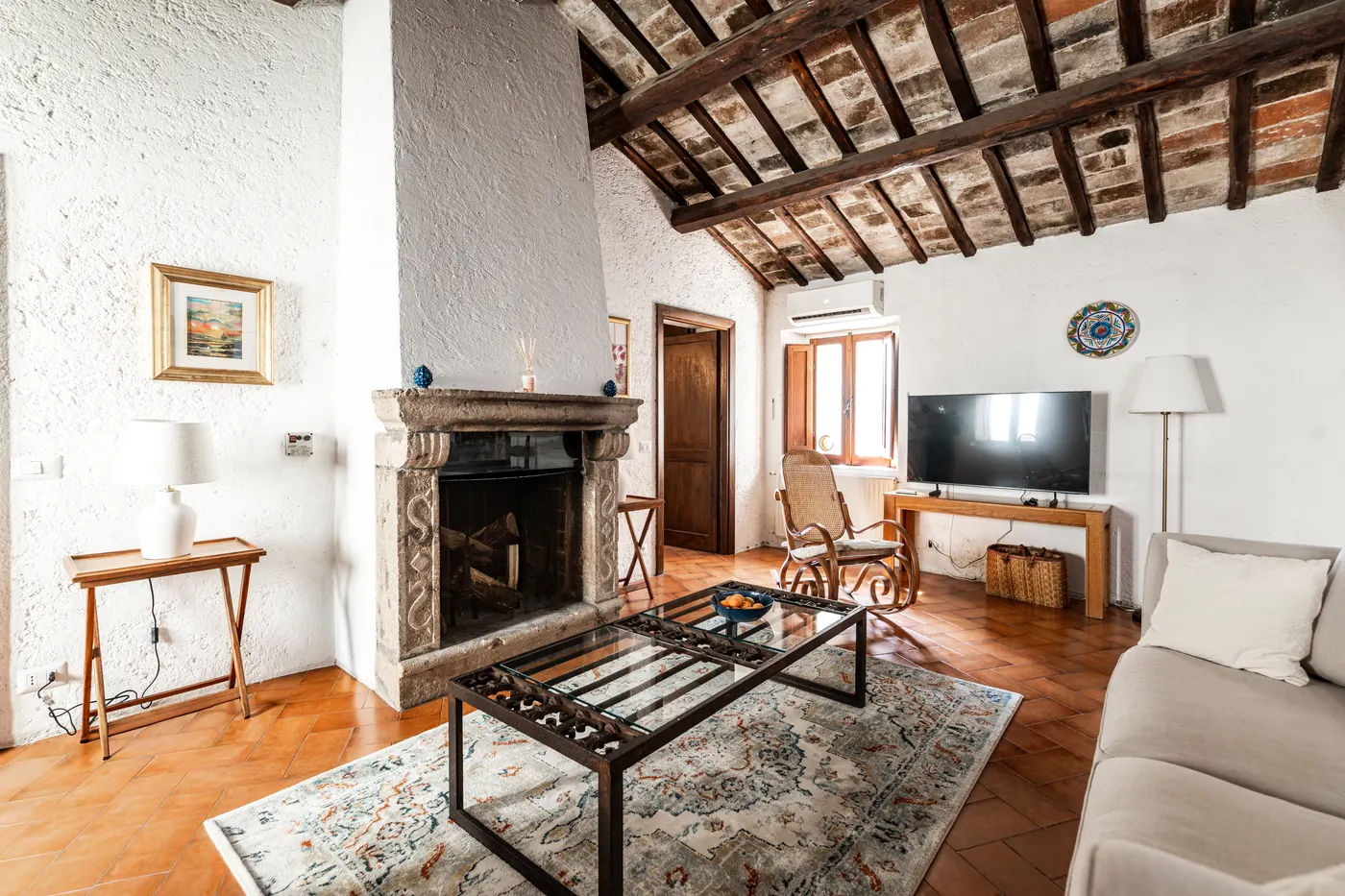 Soggiorno con camino in pietra e soffitto a travi